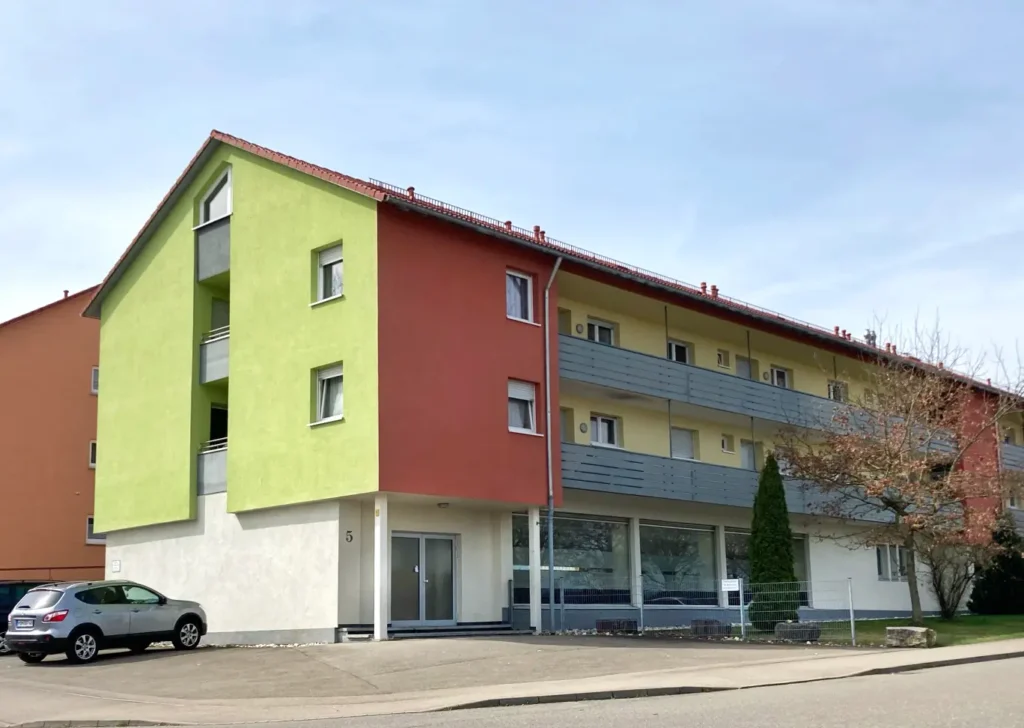 Außenansicht eines Mehrfamilienhauses in der Berliner Straße in Giengen an der Brenz. Die Fassage ist Limettengrün, Rot und Gelb.